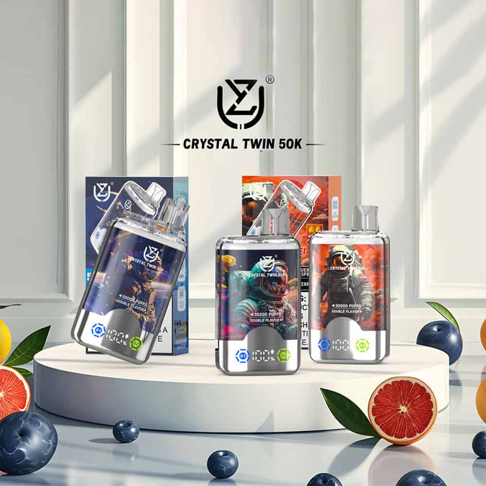 Display of Crystal Twin 50K vape devices and packaging with astronaut-themed graphics, surrounded by fruit including grapefruit slices, blueberries, and oranges in a bright, modern setting.