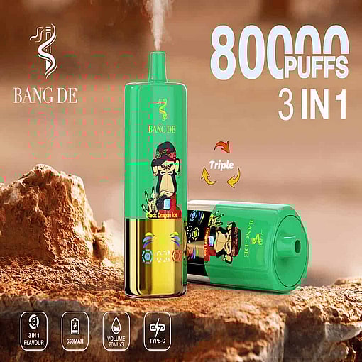 Two Green Bang De Disposable Vape Devices With A Cartoon Monkey Graphic And Gold Bottom, Placed On A Rocky Surface, Featuring '80,000 Puffs', '3 In 1', And Icons Indicating 650Mah Battery, 20Ml X3 Volume, And Type-C Charging.