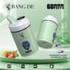 Twee groene Bang De wegwerp-vape-apparaten met een paars gorilla-logo, met een mondstuk dat damp uitstoot, pictogrammen voor drie smaken, dubbele spoel, intelligent vermogen en digitale olie-indicatoren, en afbeeldingen van aardbei, mango en kiwi die de beschikbare smaken voorstellen.