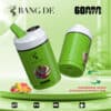Bang De Vape-apparaat in groene kleur met 60.000 trekjes, drie smaken (aardbei-mango, watermeloen, kauwgom), dubbele spoel, intelligente stroom- en olie-indicatoren en productbranding met een cartoon-aaplogo.